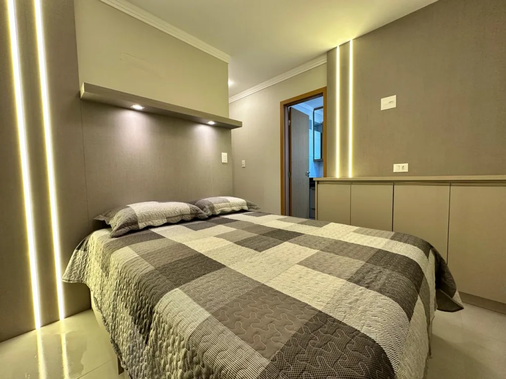 Dormitório de apartamento decorado com cama de casal e iluminação embutida
