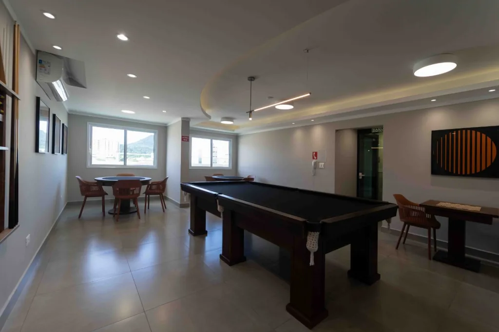 Salão de jogos do condomínio com mesa de sinuca e mesa de jogos