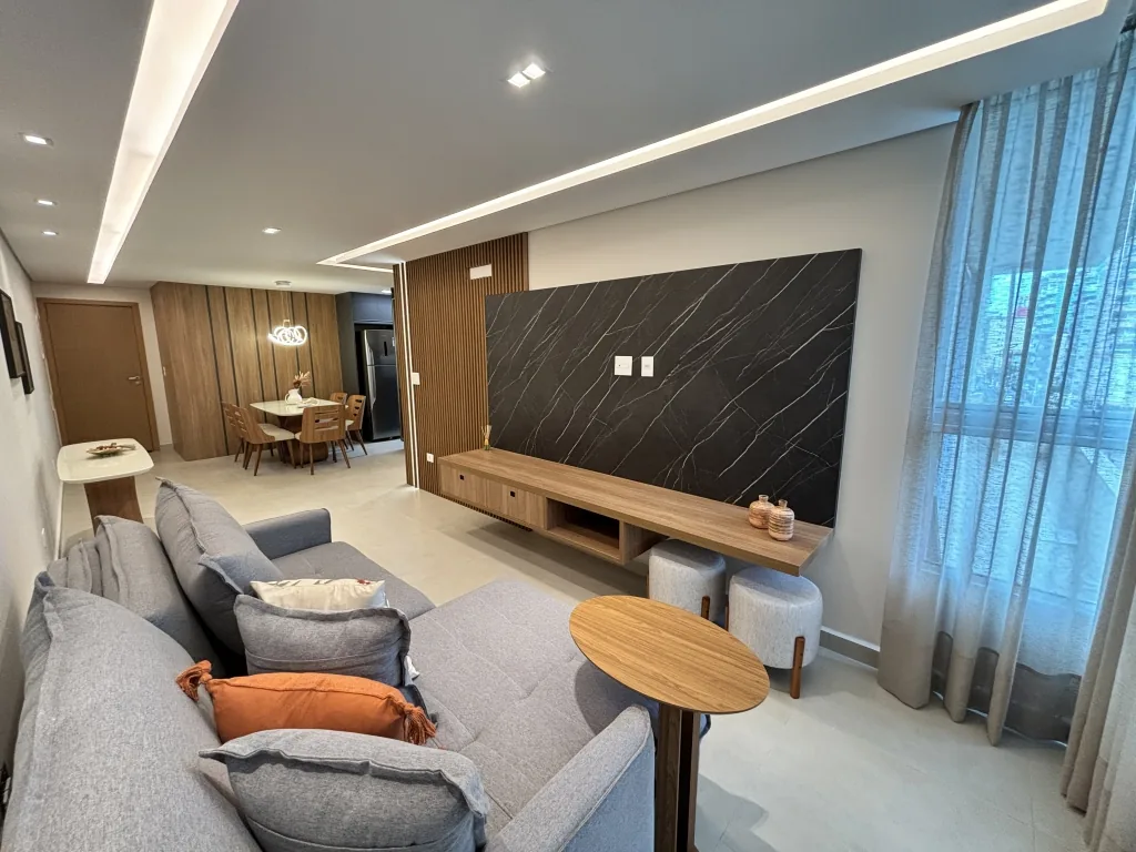 Living de apartamento decorado com sofá e painel de TV